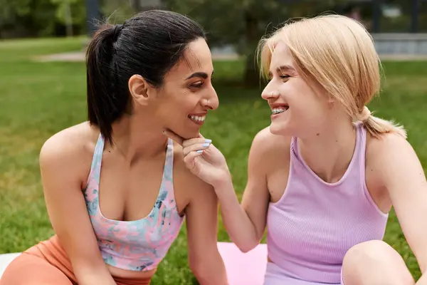Duas mulheres sorriem amorosamente uma para a outra, aproveitando seu tempo em um ambiente exuberante parque verde. — Fotografia de Stock