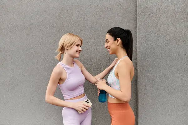 Two young women share a joyful moment, smiling and engaging after a workout session together. — Stock Photo