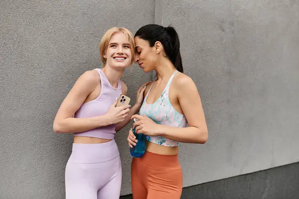 Two joyful young women share a sweet moment together after a workout, embracing love and fitness. — Stock Photo