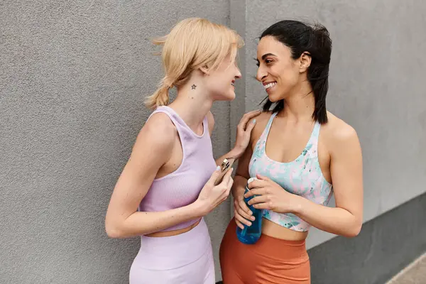 Zwei junge Frauen lächeln und verbinden sich, während sie nach ihrem Training im Freien eine Pause einlegen. — Stockfoto