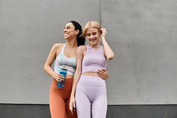 Dos mujeres jóvenes disfrutan de una divertida sesión de entrenamiento juntas, irradiando amor y felicidad. - foto de stock