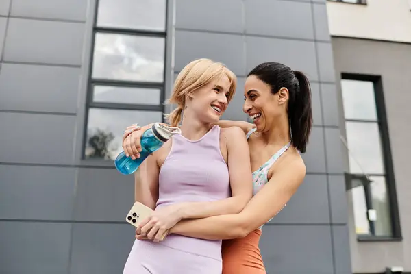 Two young women embrace lovingly, sharing smiles and laughter during their outdoor workout. — Stock Photo