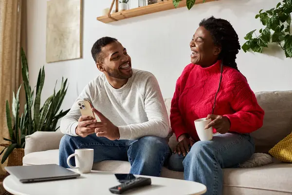 A happy couple enjoys quality time together at home, sipping drinks and wearing cozy sweaters. — Stock Photo