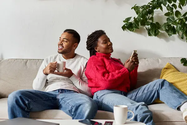 Ein glückliches afroamerikanisches Paar genießt einen gemütlichen Wintertag zusammen, entspannt in seinem Wohnzimmer. — Stockfoto