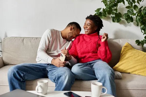 Un heureux couple afro-américain partage le rire et la chaleur dans leur salon pendant l'hiver. — Photo de stock