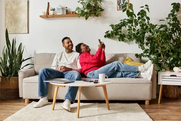 A delighted African American couple relaxes together on the sofa, enjoying their cozy winter day. — Stock Photo