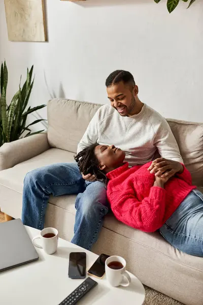 A warm and loving couple enjoys quality time together on a cozy couch while winter surrounds them. — Stock Photo