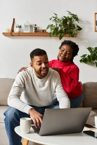 A joyful African American couple shares warmth and laughs while working on a laptop at home. — Stock Photo