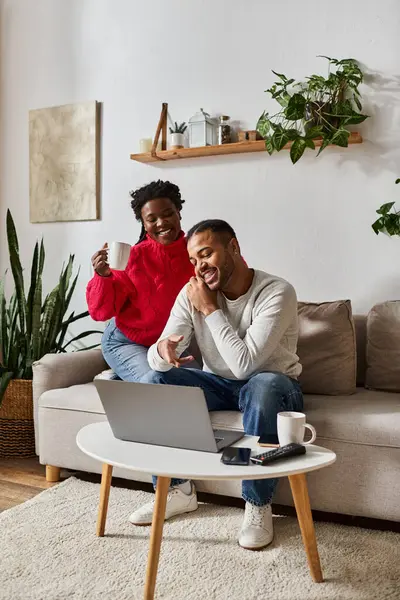 A happy couple enjoys quality time together at home, sipping drinks and looking at laptop — Stock Photo