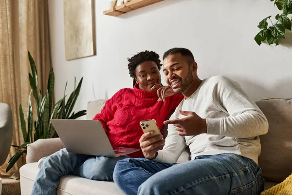 Un couple heureux profite de temps de qualité ensemble dans leur salon confortable, souriant à un téléphone. — Photo de stock