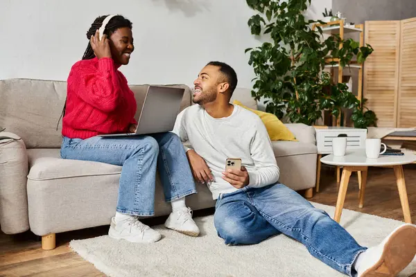 A joyful African American couple shares quality time at home while wearing warm sweaters. — Stock Photo