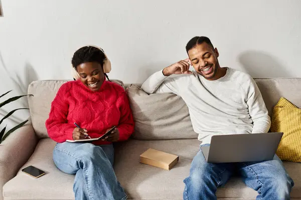 Una alegre pareja afroamericana comparte tiempo de calidad en casa, relajada y sonriente. - foto de stock