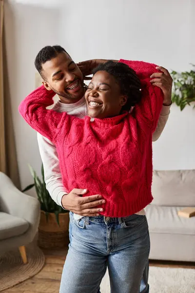 Un couple heureux embrasse chaleureusement, partageant le rire dans leur salon confortable pendant l'hiver. — Photo de stock