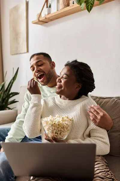 Ein glückliches Paar teilt einen warmen Moment an einem Winterabend, genießt Popcorn und die Gesellschaft der anderen. — Stockfoto