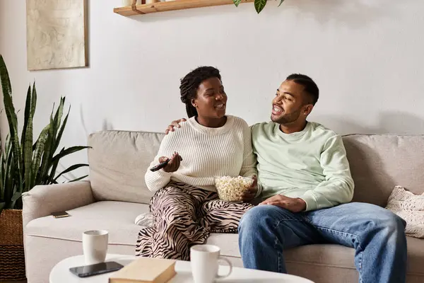 Una coppia amorevole si gode reciprocamente compagnia, condividendo sorrisi e popcorn nel loro accogliente soggiorno. — Foto stock