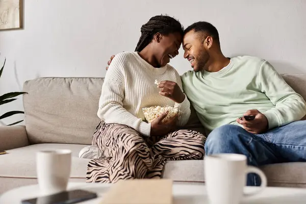 Una coppia felice gode di tempo di qualità insieme mentre condivide risate e popcorn a casa. — Foto stock