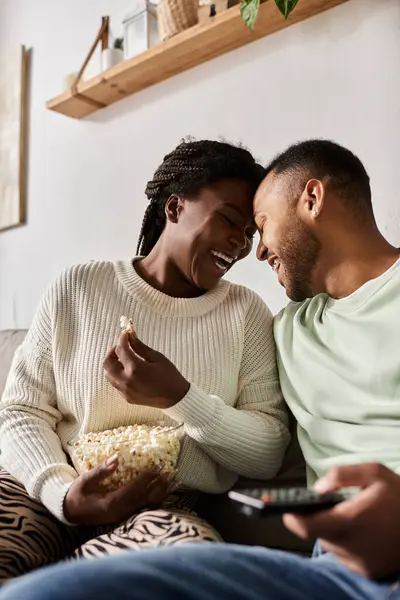 Felice coppia gode ogni altri compagnia a casa mentre la condivisione di popcorn e risate. — Foto stock