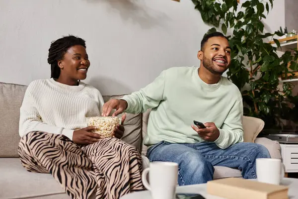 Una coppia si gode il tempo di qualità insieme in una serata invernale, condividendo risate e popcorn. — Foto stock