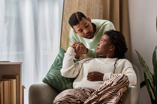 Afro-américain homme réconfortant sa petite amie inquiète tout en se tenant la main dans leur salon confortable — Photo de stock