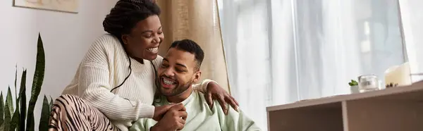 Радостная пара обнимает тепло и любовь в уютном доме зимой, делясь смехом. — стоковое фото