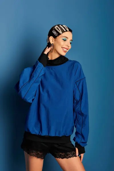 A stylish young woman displays her vibrant blue outfit against a matching backdrop. — Stock Photo