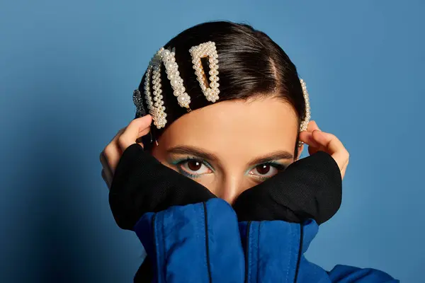 A young woman playfully poses in the studio, showing off her trendy outfit and hair clips. — Stock Photo