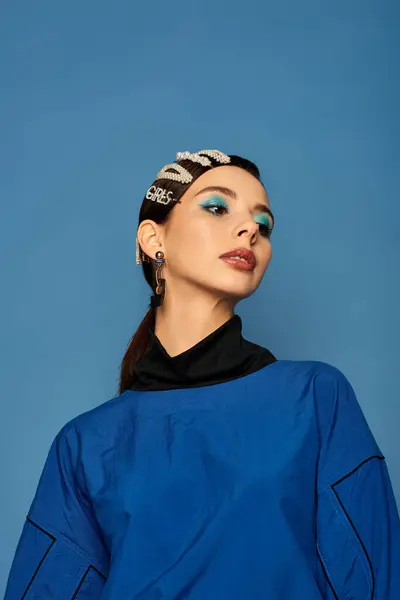 Молода і модна жінка виявляє впевненість у модному вбранні з зачісками, встановленими проти синього. — стокове фото