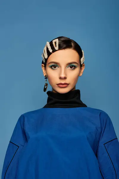 A fashionable young woman poses confidently in a striking blue outfit with stylish hair clips. — Stock Photo