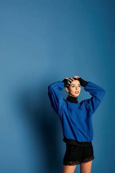 A beautiful young woman with hair clips showcases her trendy outfit in a studio setting. — Stock Photo