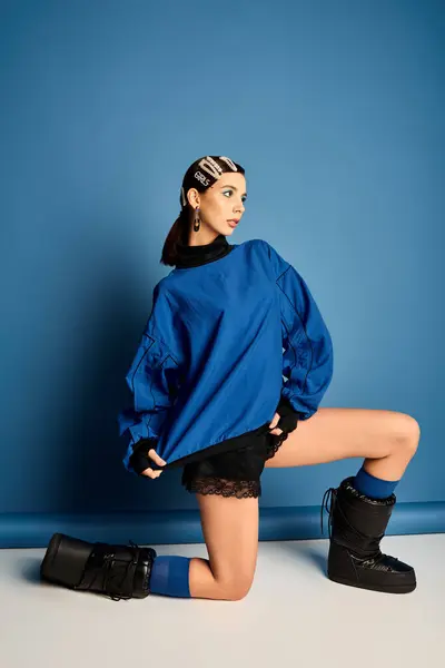 Una giovane donna elegante posa elegantemente nel suo vestito su uno sfondo blu. — Foto stock
