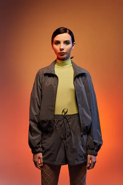 Stylish young woman poses confidently in a trendy outfit against a striking gradient background. — Stock Photo