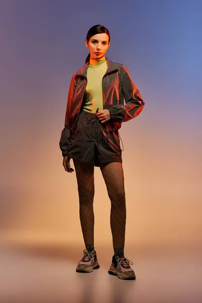 A stylish woman poses confidently in a trendy outfit with a vibrant gradient backdrop. — Stock Photo