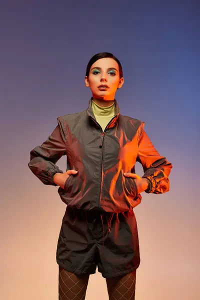 Young woman showcases a trendy outfit, expressing confidence against a vibrant background. — Stock Photo