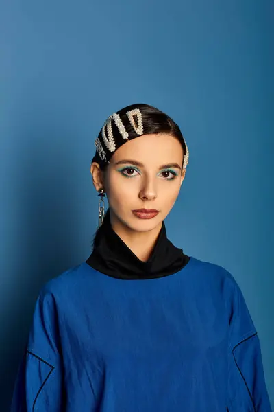 A young woman showcases her trendy attire and accessories in a vibrant blue studio setting. — Stock Photo