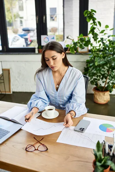 Brunette woman focused on work, examining documents while enjoying a warm cup of coffee — Stock Photo