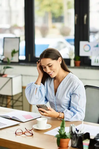 A young beautiful woman dressed in a light blue blouse enjoys her time with a smartphone. — Stock Photo
