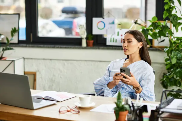Young woman with brunette hair focused on her phone amidst a vibrant workspace filled with plants. — Stock Photo