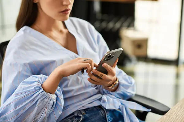 Brunette woman in trendy blouse interacts with smartphone in a modern office setting. — Stock Photo