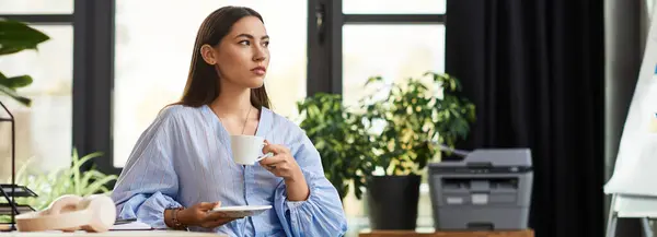 Beautiful brunette woman sips coffee with contemplation in a stylish, light filled room. — Stock Photo