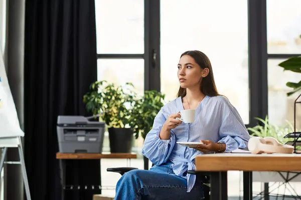 A young brunette woman sips coffee in a serene, green workspace. — Stock Photo
