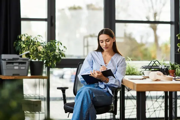 Beautiful brunette woman writes in her notebook at a bright and inspiring office space. — Stock Photo