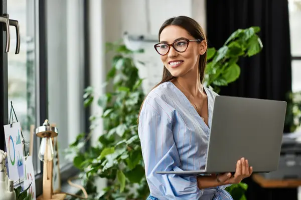A bright workspace features a smiling young brunette using her laptop thoughtfully. — Stock Photo
