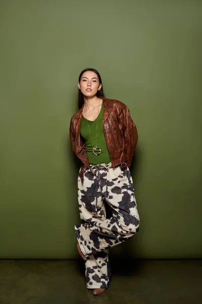Beautiful young woman poses stylishly in cow print pants and a green top, radiating charm. — Stock Photo
