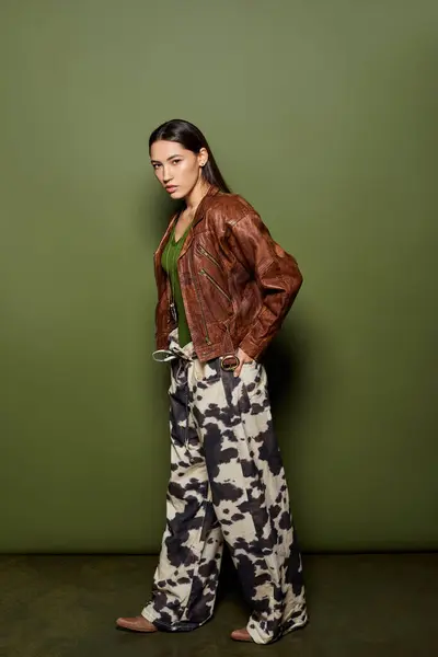 Young beautiful woman poses confidently in a trendy outfit against a green backdrop. — Stock Photo