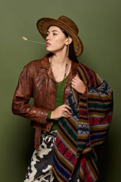 Brunette woman wearing a leather jacket holds a colorful patterned shawl while posing confidently. — Stock Photo