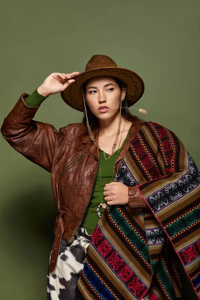 Mujer morena posa con confianza, usando prendas tradicionales llamativas y un sombrero con estilo. - foto de stock