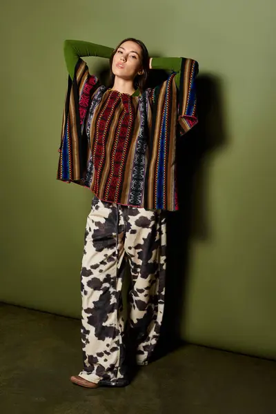 Brunette woman showcases vibrant clothing while posing confidently in an artistic environment. — Stock Photo