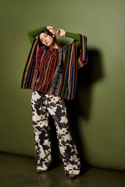 Striking young woman models a colorful bohemian ensemble with flair under soft lighting. — Stock Photo