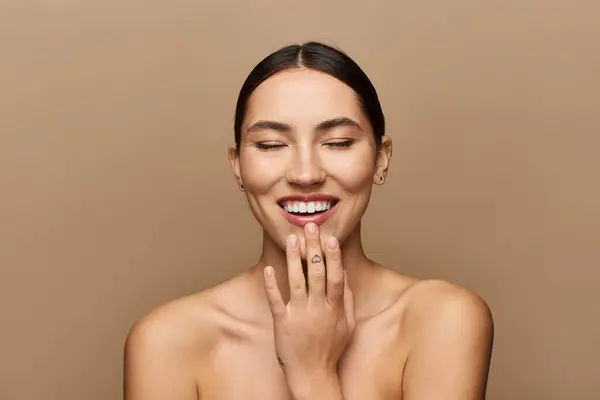 Brunette woman beams joyfully, highlighting her beauty in a warm, neutral setting. — Stock Photo