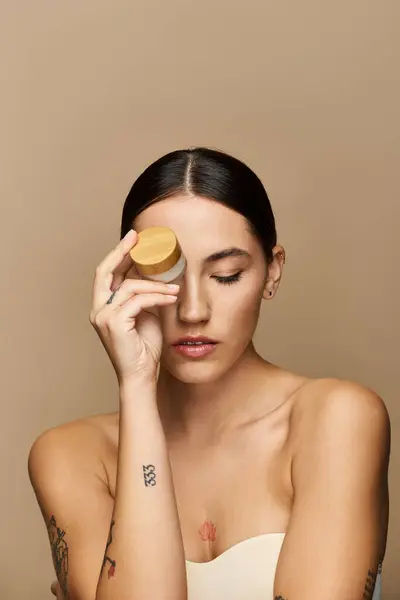 A young brunette applies skincare, showcasing her radiant glow and confidence. — Stock Photo